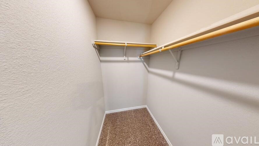 A small, empty closet with a carpeted floor and two wooden shelves.