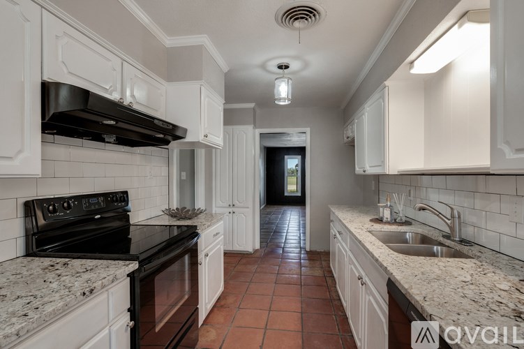 A kitchen with white cabinets and a black stove top oven.