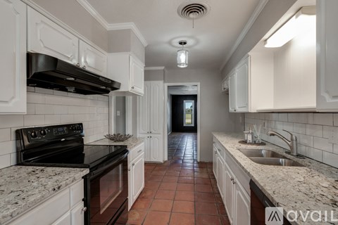 A kitchen with white cabinets and a black stove top oven.