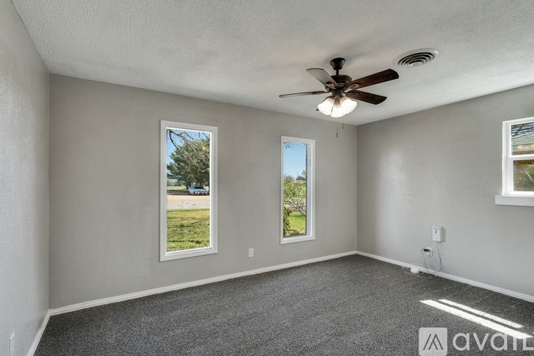A room with a ceiling fan and two windows.