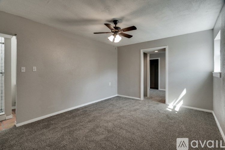 A room with a ceiling fan and carpeted floor.