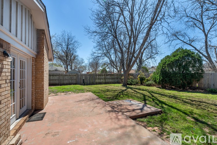 A backyard with a concrete patio and a tree.
