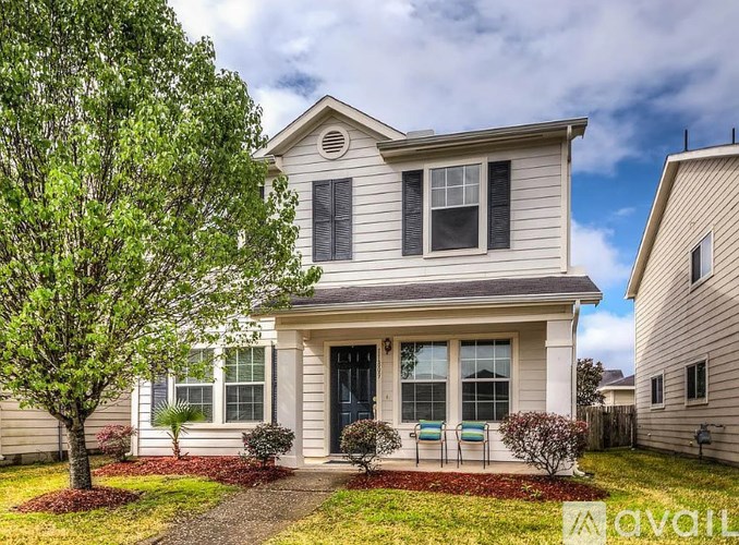 A two-story house with a front yard and a tree.