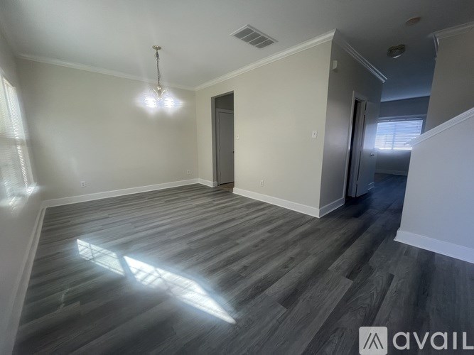 A spacious room with wooden flooring and a single door.