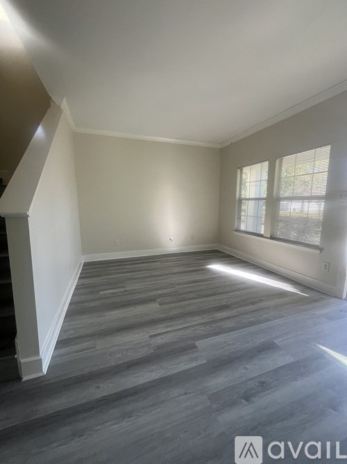 A room with wooden flooring and a window letting in natural light.