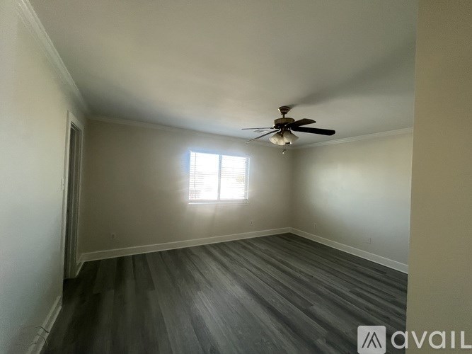 A room with a ceiling fan and a window letting in light.