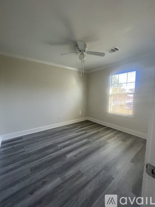 A room with a ceiling fan and a window letting in light.