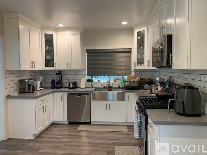 A kitchen with white cabinets and a wooden floor.