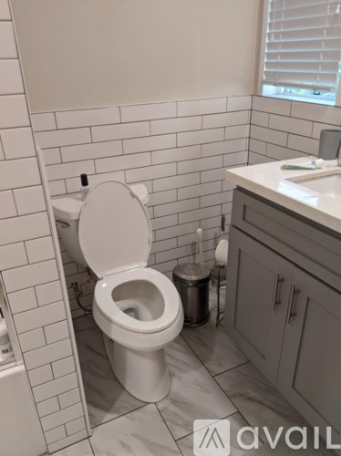 A white toilet in a bathroom with a white tiled wall.