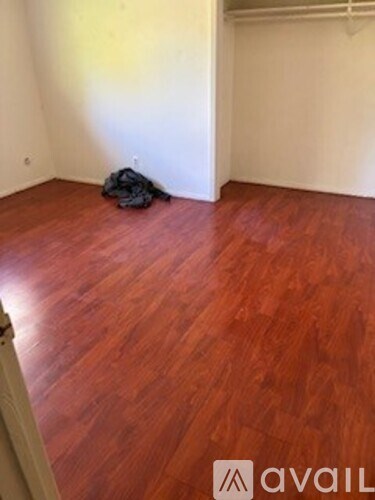 A room with a wooden floor and a black bag.
