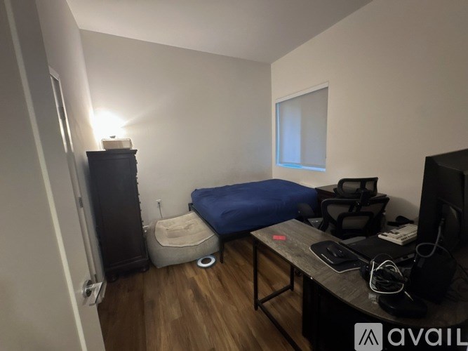 A room with a bed, desk, and a television.