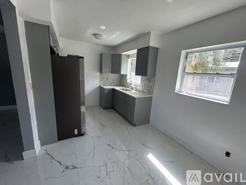 A kitchen with a marble floor and a window showing a view of a street.