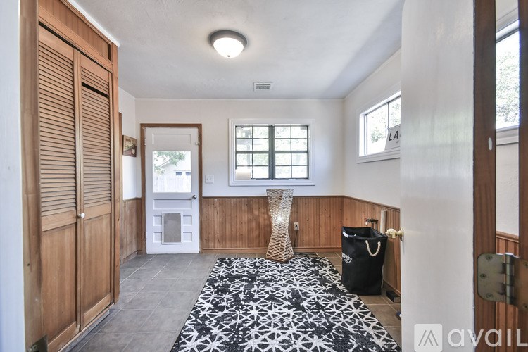 A room with a black and white patterned carpet, wooden walls, and a window with blinds.