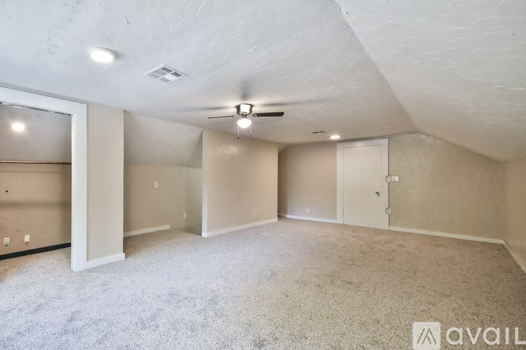 A spacious room with a ceiling fan and carpeted floor.