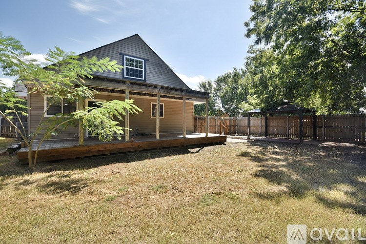 A house with a deck and a tree in front.