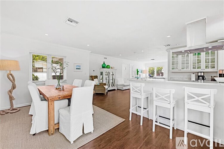 A modern kitchen with white chairs and a wooden dining table.