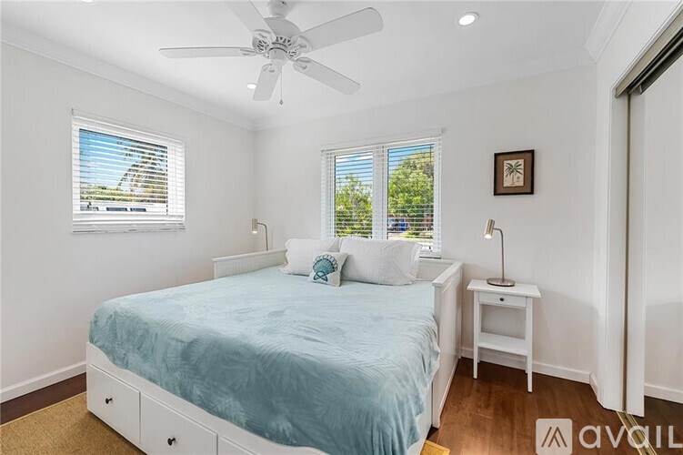 A bedroom with a bed, a nightstand, and a window with blinds.