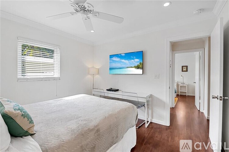 A bedroom with a bed, a television, and a ceiling fan.
