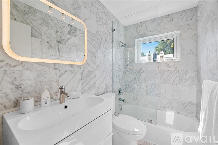 A bathroom with a marble wall and a window showing a tree.