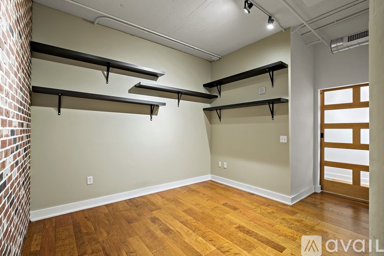 A room with wooden floors and a brick wall on the left side.