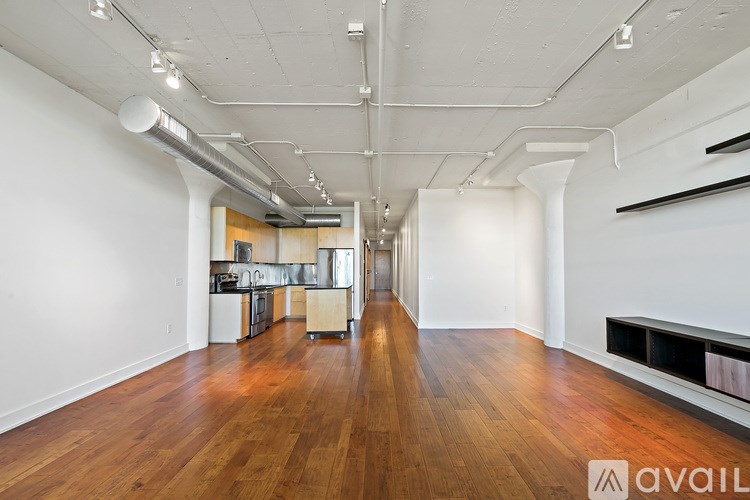 A long, empty room with wooden floors and white walls.