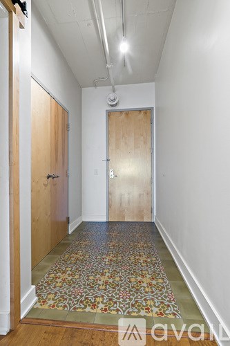 A hallway with a rug on the floor and a door on the right.
