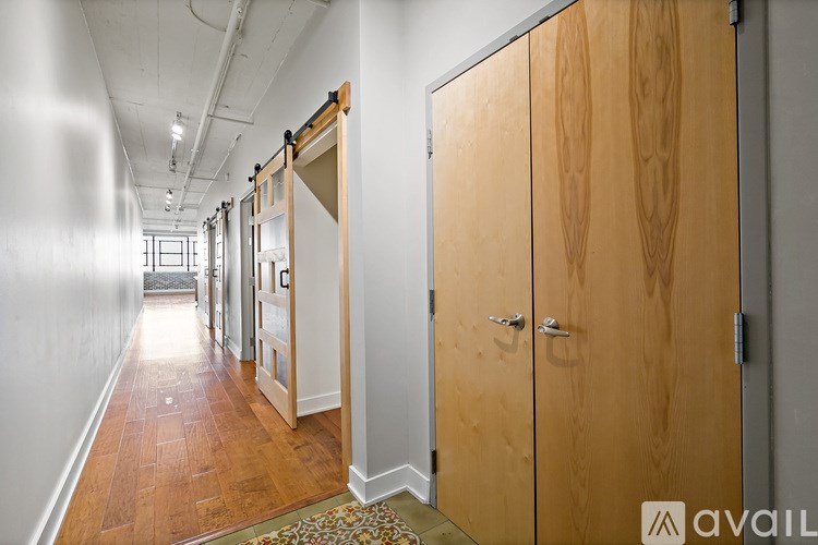 A hallway with wooden doors and a rug on the floor.