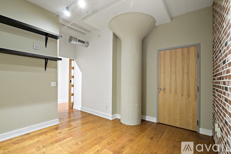 A room with a wooden floor and a brick wall.