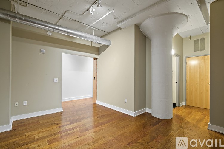 A room with wooden floors and a white column in the middle.
