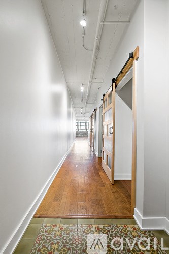 A long hallway with a rug on the floor and doors on the right.