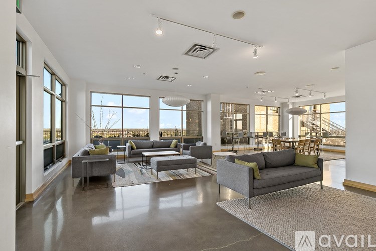 A spacious living room with grey sofas and a large window overlooking a snowy landscape.