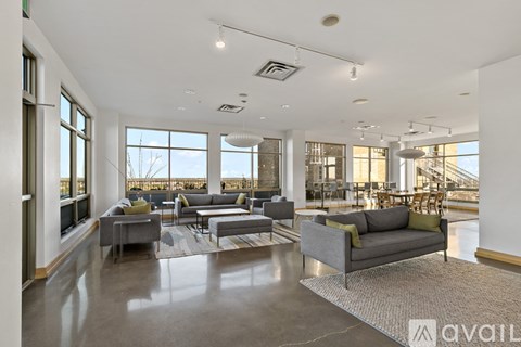A spacious living room with grey sofas and a large window overlooking a snowy landscape.