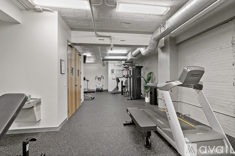 A gym with a treadmill, weights, and exercise equipment.