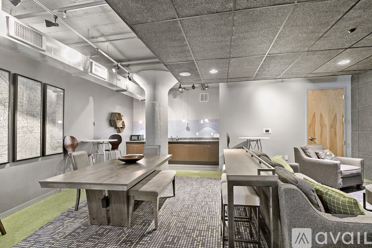 A modern office space with a long table and chairs, a couch, and a green carpet.