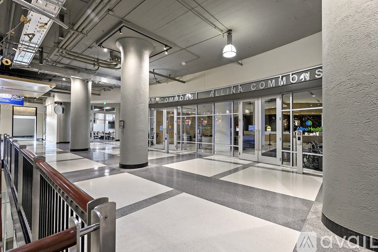The image shows a spacious lobby with a checkered floor, a glass door entrance, and a sign that reads "Allianz Commons."
