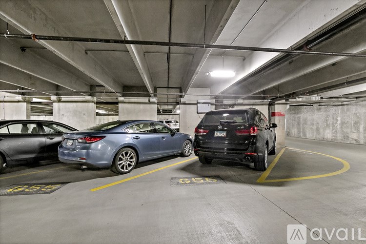 A parking garage with a black car parked in the middle of the frame.