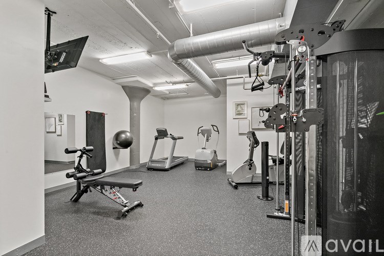 A gym with a variety of equipment including a rowing machine, a bench press, and a leg press.