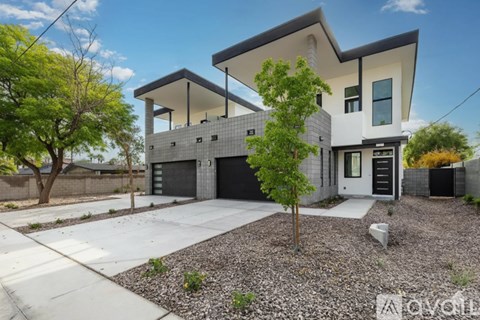 A modern two-story house with a garage and a tree in front.