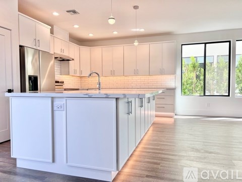 A modern kitchen with white cabinets and a wooden floor.