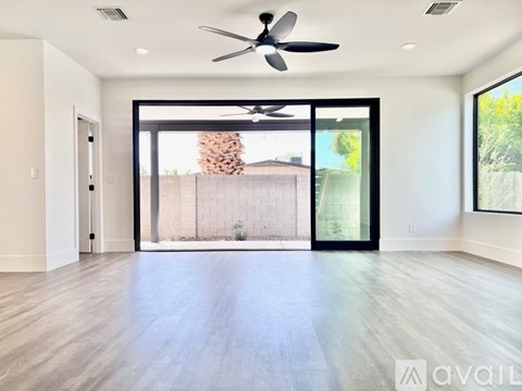 A spacious room with a ceiling fan and sliding glass doors leading to a backyard.