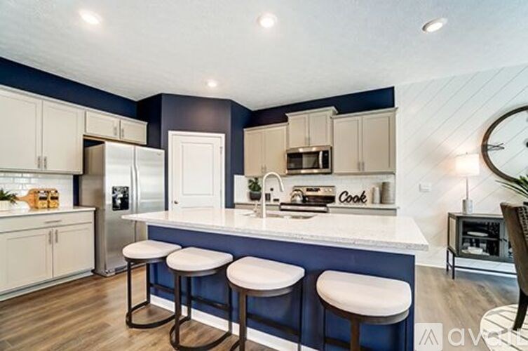 A kitchen with white cabinets and a blue backsplash with a fridge, microwave, and stove top oven.