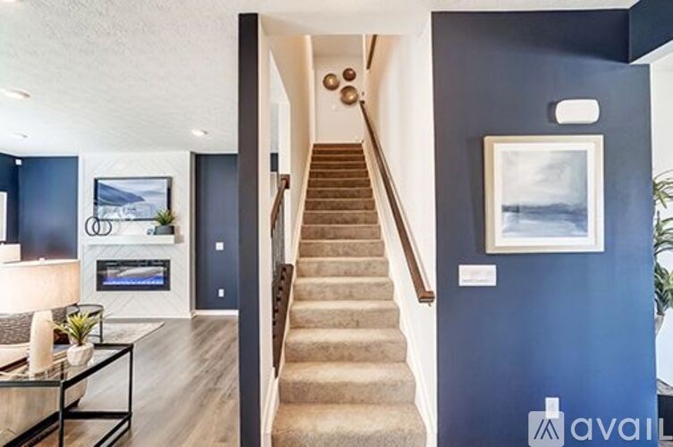 A staircase in a house with a blue wall and a painting hanging on it.
