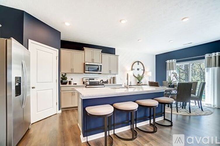 A kitchen with a bar stool and a fridge.