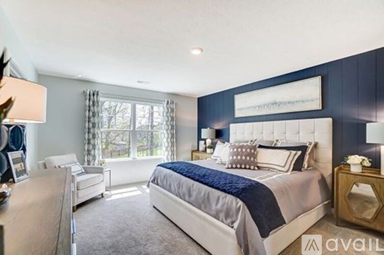 A bedroom with a large bed and a window with curtains.