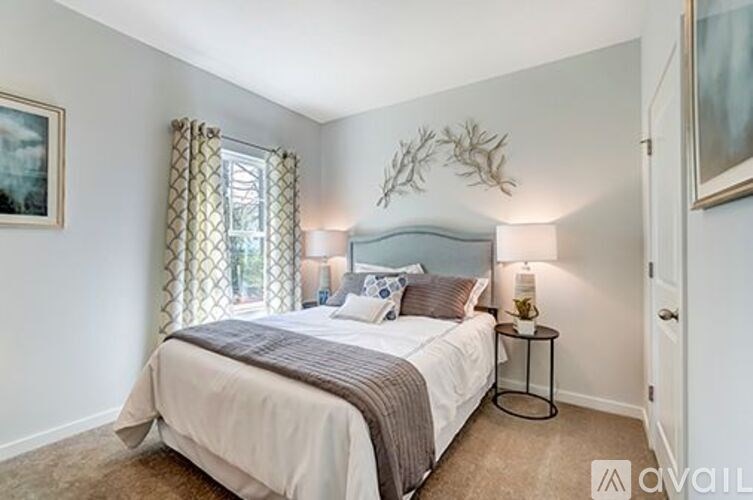 A bedroom with a large bed and a window with curtains.