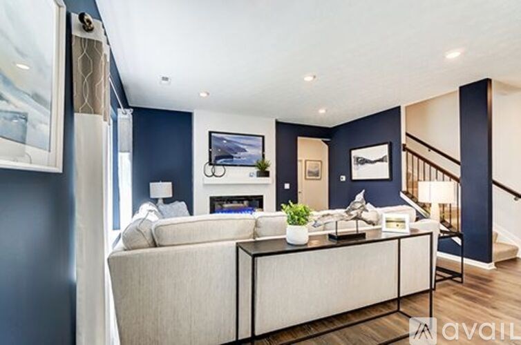 A living room with a white sofa and a TV on the wall.