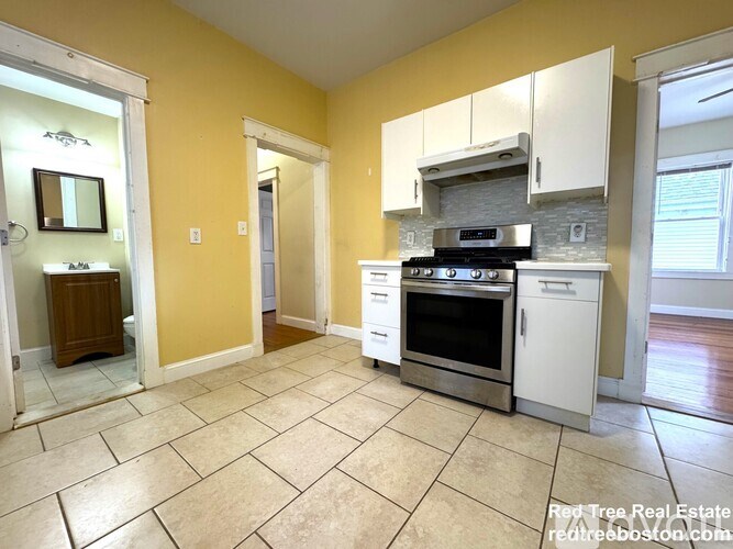 A kitchen with yellow walls and white cabinets.