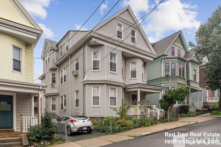 A row of houses with a car parked in front of the first house.