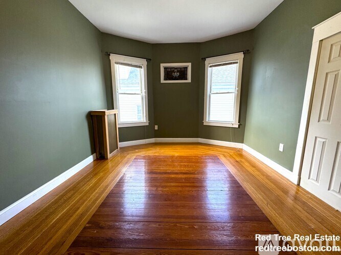 A room with wooden floors and two windows.