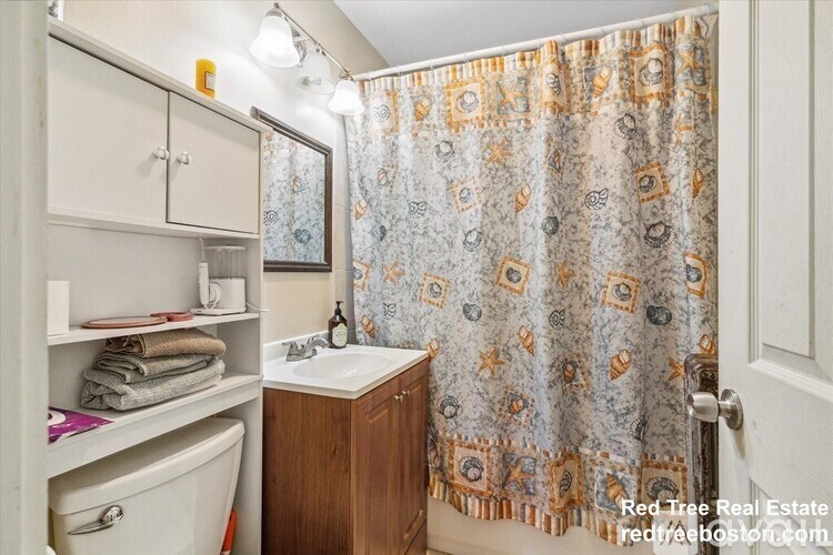 A bathroom with a shower curtain and a sink.